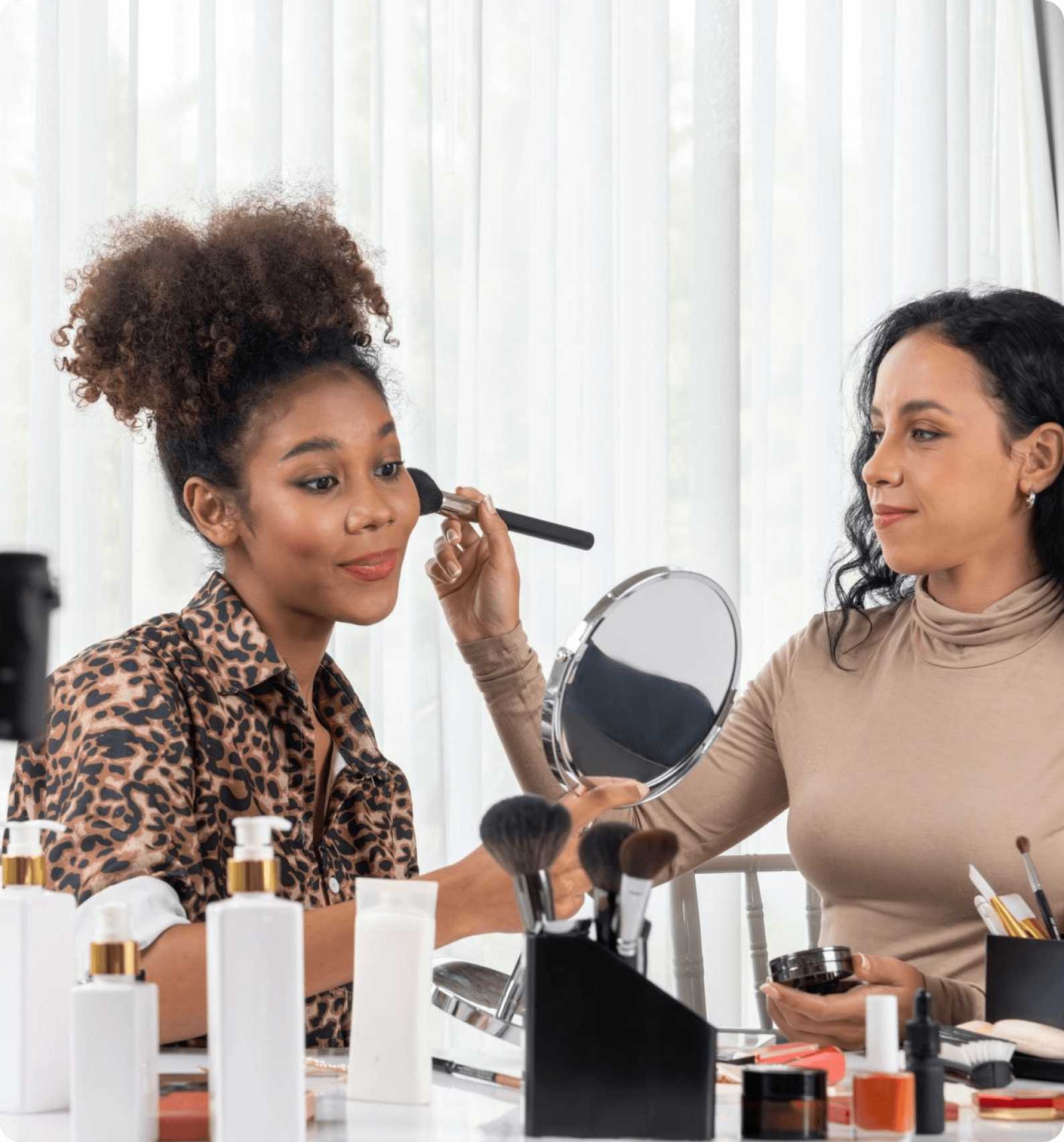 A makeup artist working on a client in front of a mirror